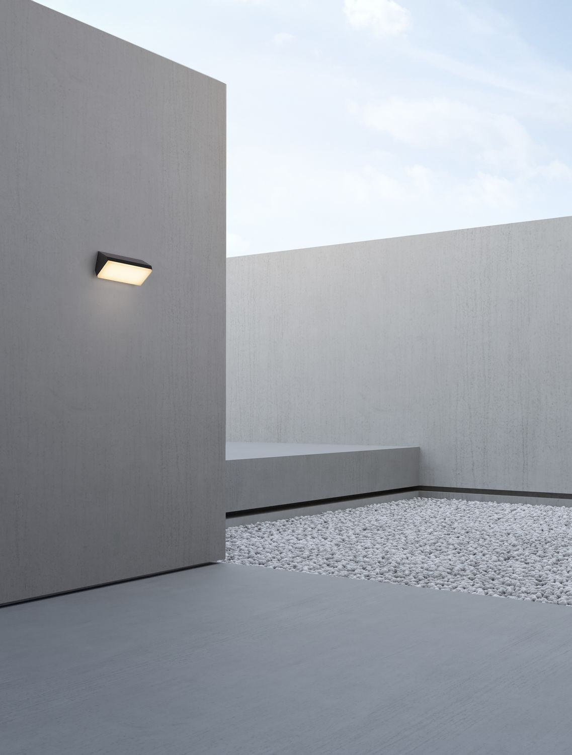 Mise en ambiance extérieure : applique allumée sur un mur de béton brut