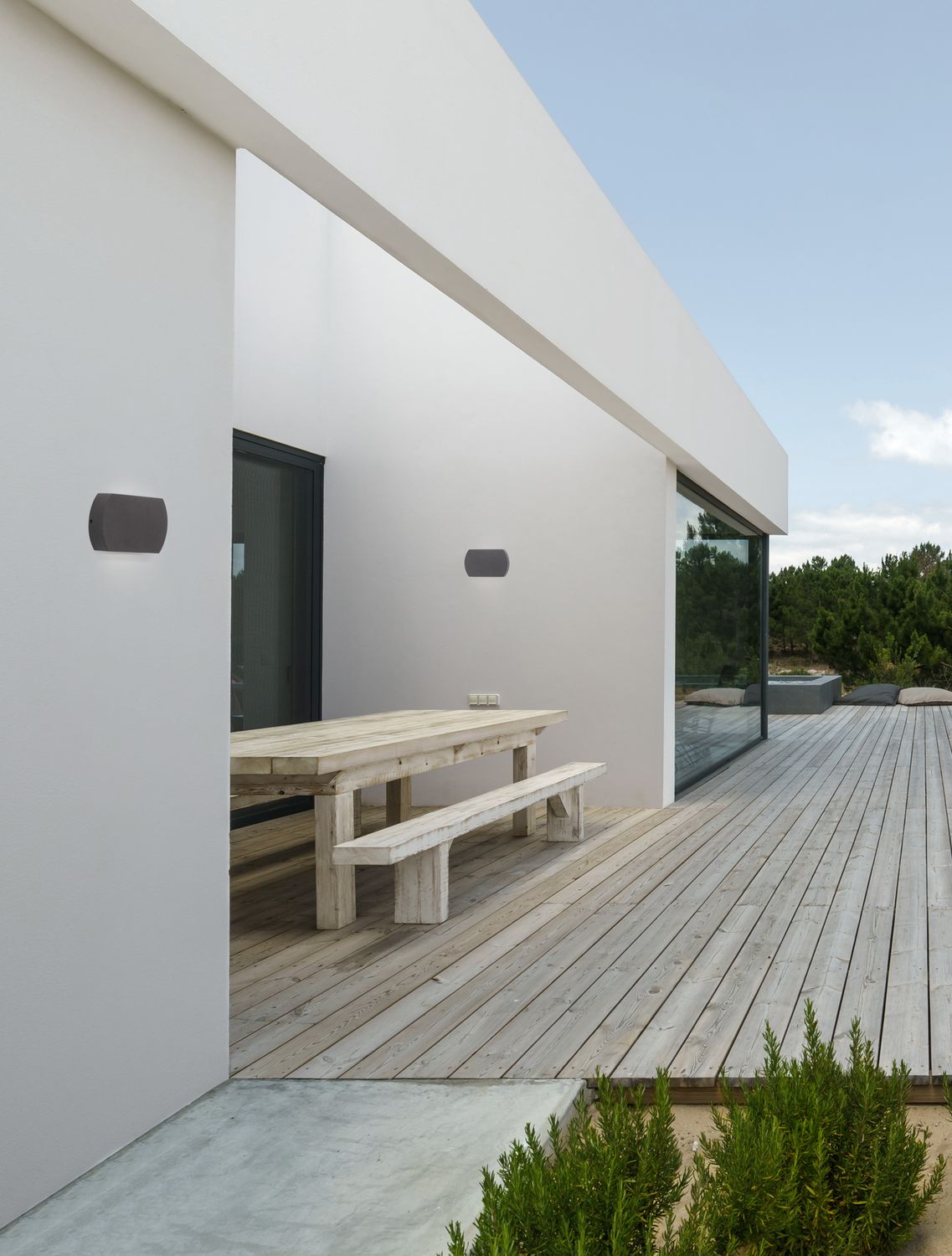 Mise en ambiance extérieure d'une terrasse avec deux appliques anthracite sur mur blanc