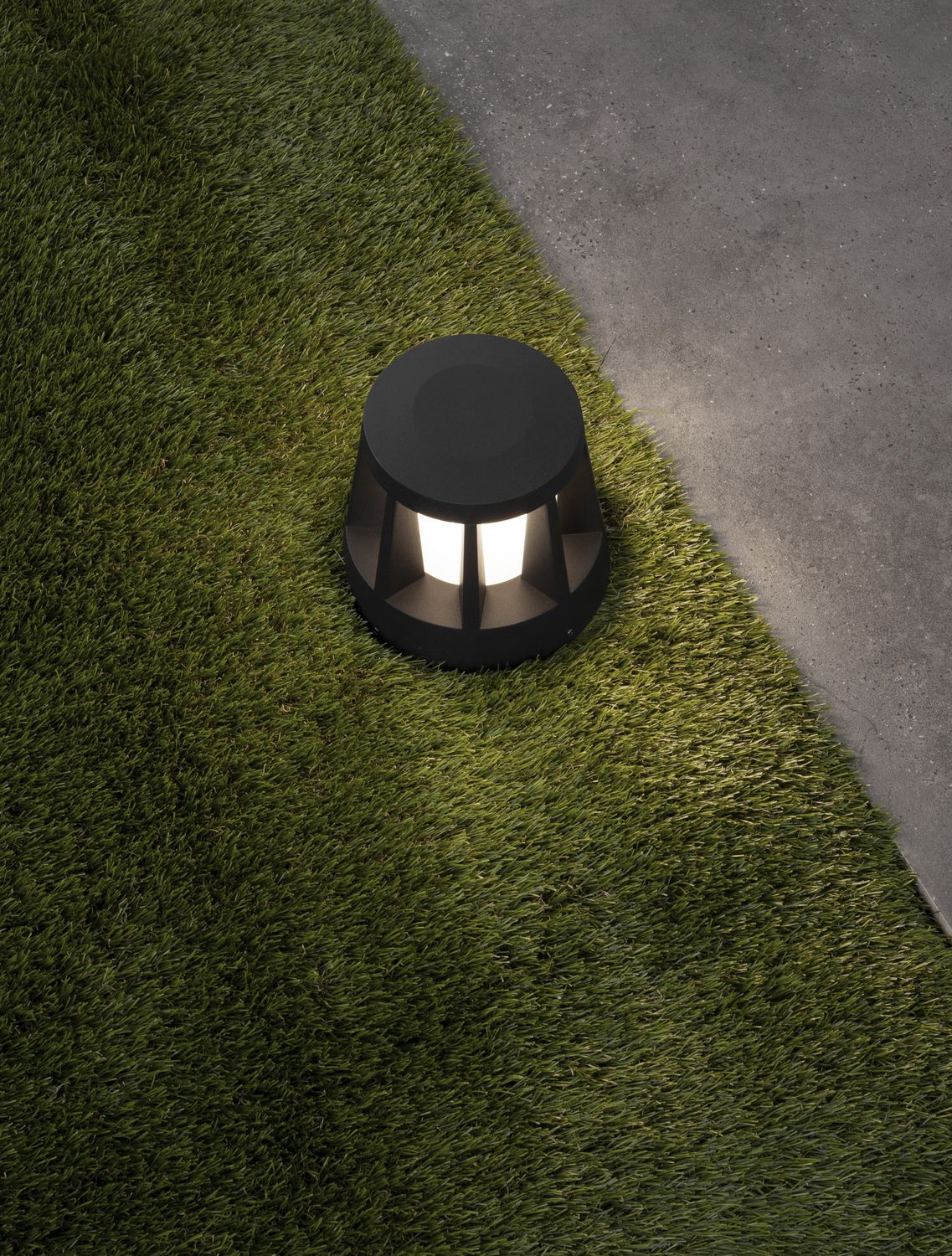 Luminaire allumé sur la pelouse, lumière chaude diffusée vers le sol