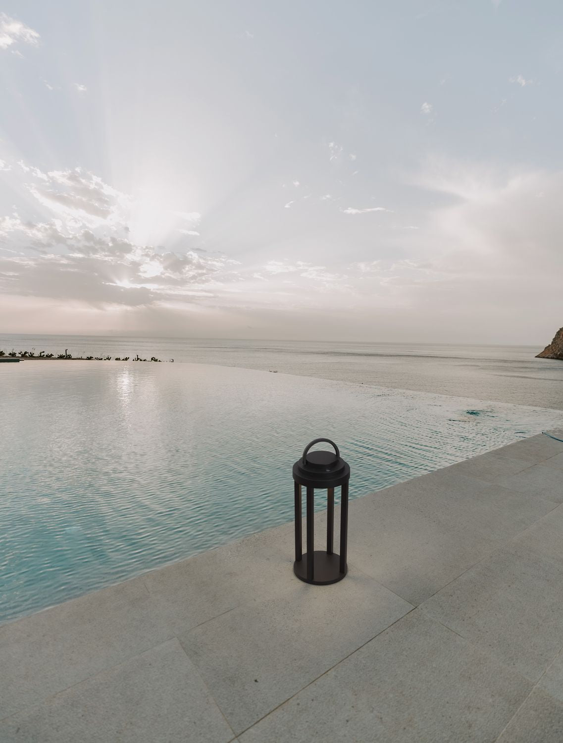 Lampadaire solaire posé au bord d'une piscine face à la mer