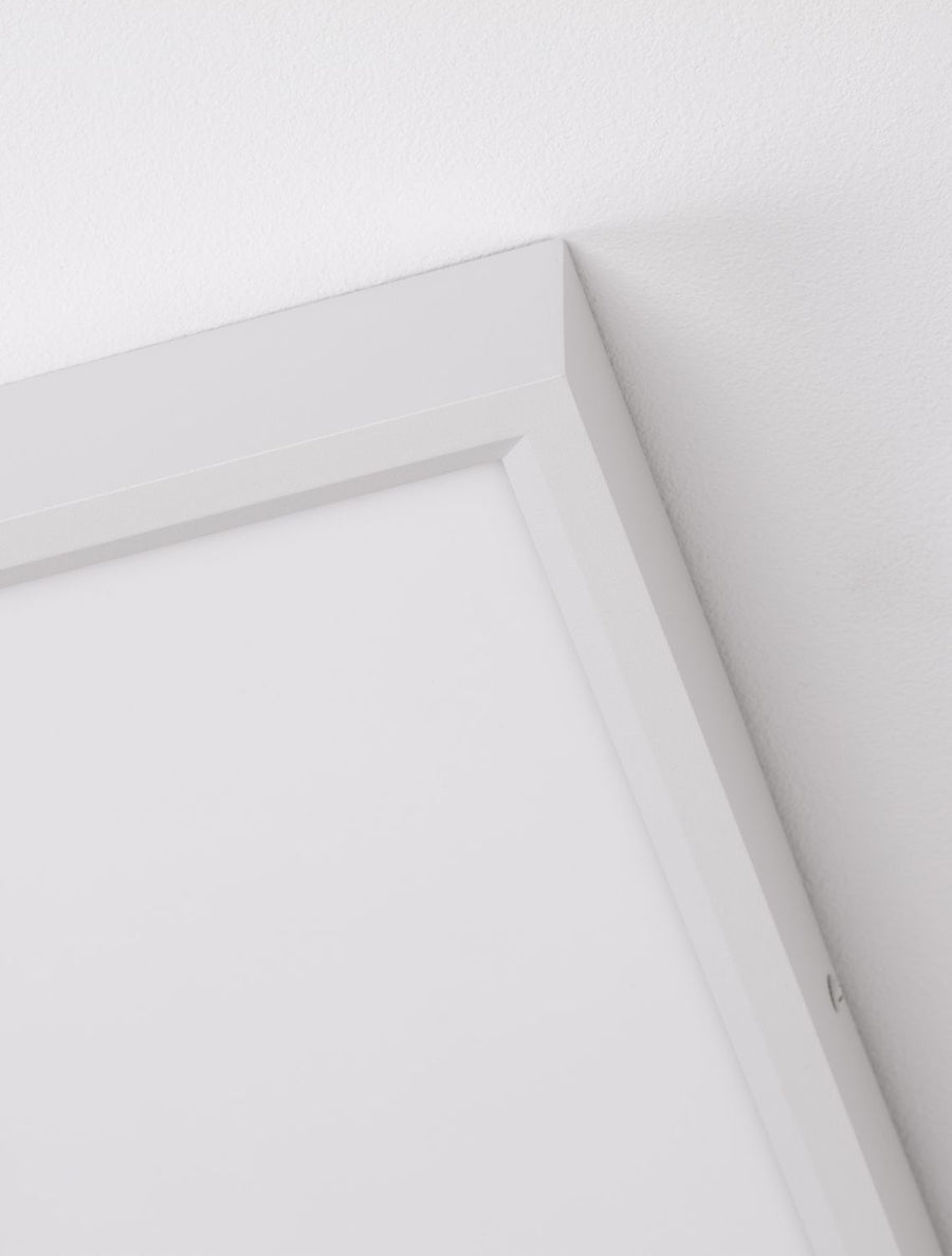 Détail rapproché d'un angle du cadre blanc et du diffuseur mat sous le plafond
