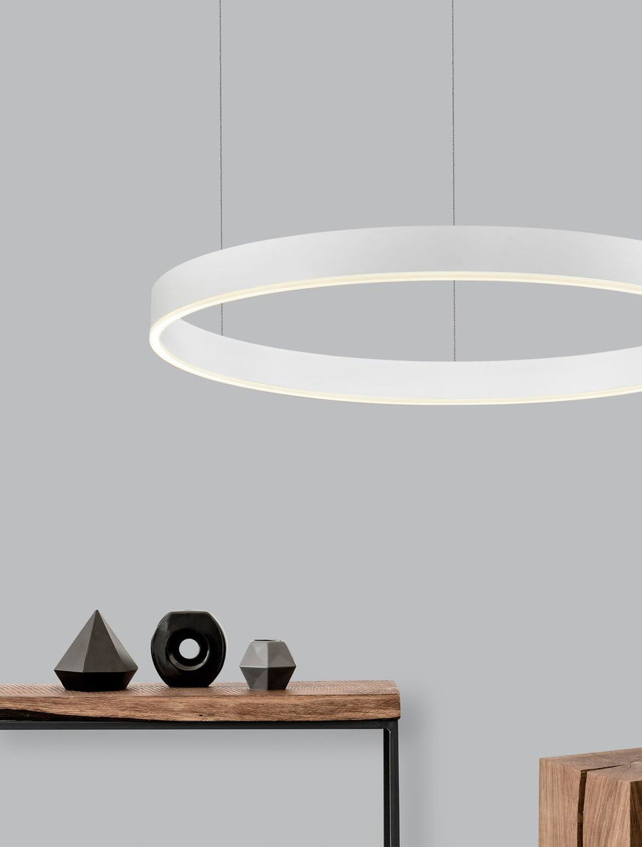 Suspension anneau blanc allumé au-dessus d'une console en bois et objets noirs.