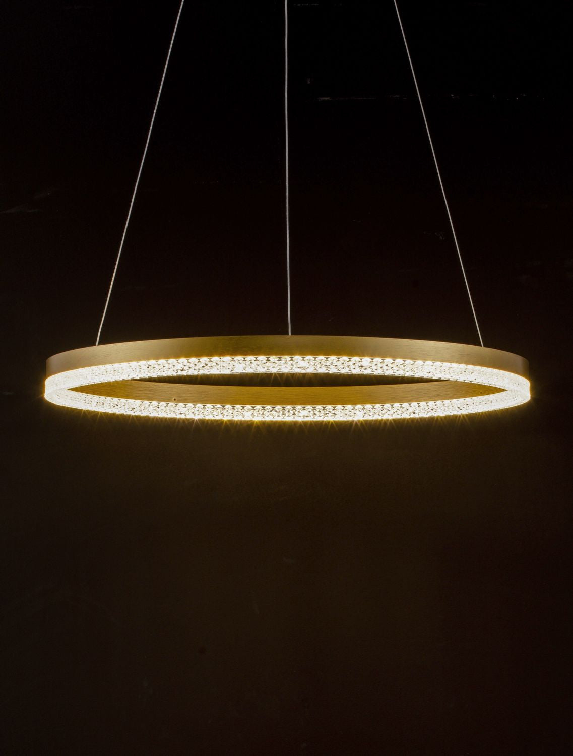 Mise en ambiance nocturne : suspension allumée, halo doré et lumière chaude dans pièce sombre.