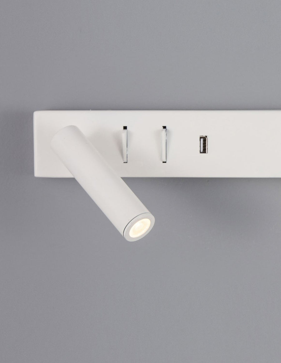 Détail rapproché du spot orientable et des interrupteurs chromés sur fond gris