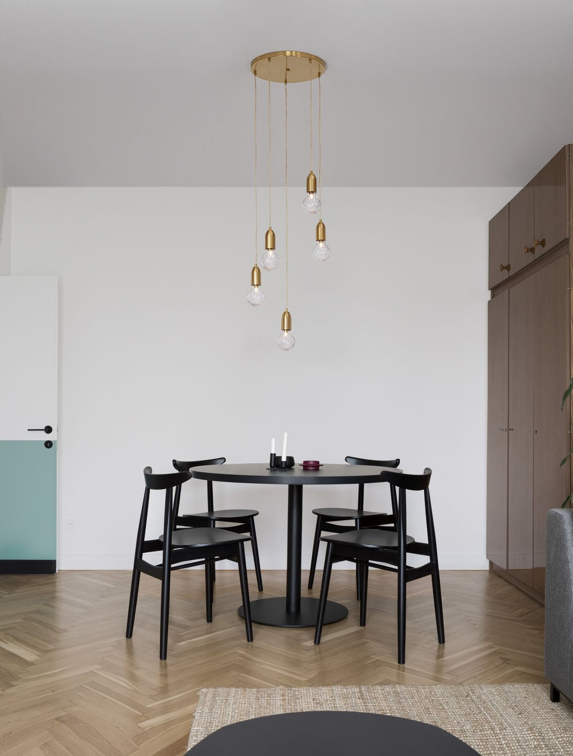 Suspension laiton à cinq lumières suspendue au-dessus d'une table à manger noire