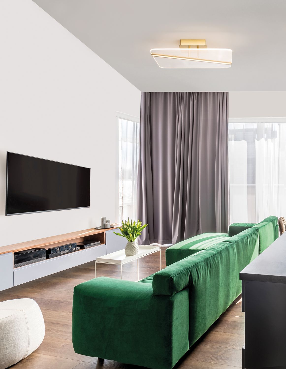 Plafonnier doré et blanc installé au plafond dans un salon moderne avec canapé vert