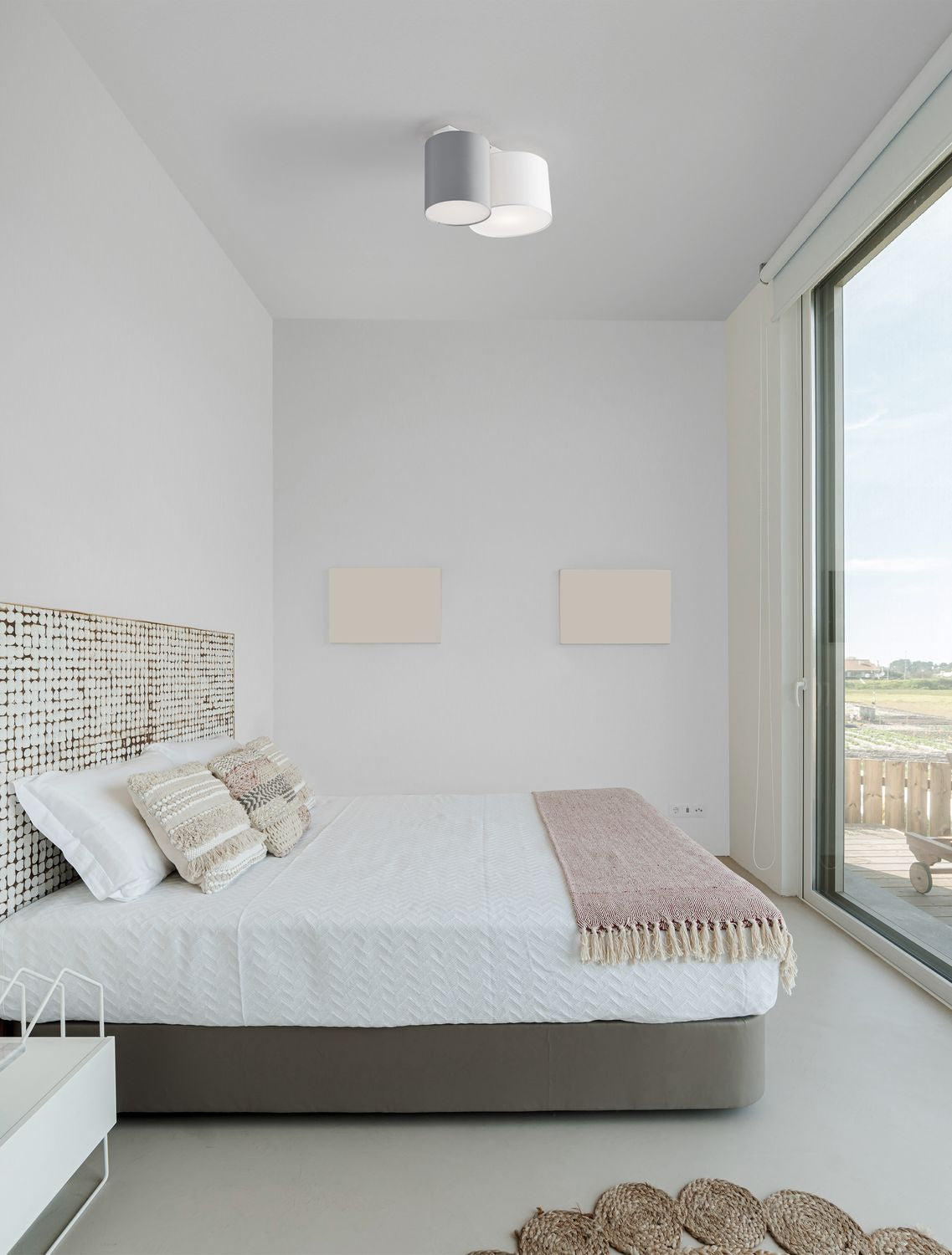 Plafonnier deux cylindres gris et blanc installé au plafond d'une chambre claire