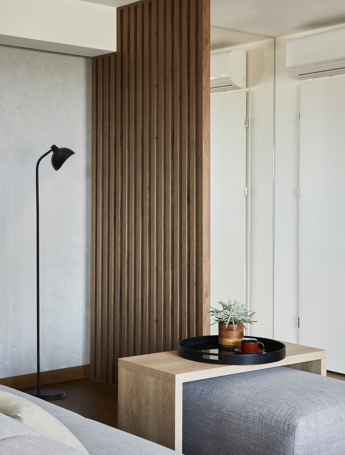 Lampadaire noir installé près d'un mur lambris bois dans un salon contemporain.