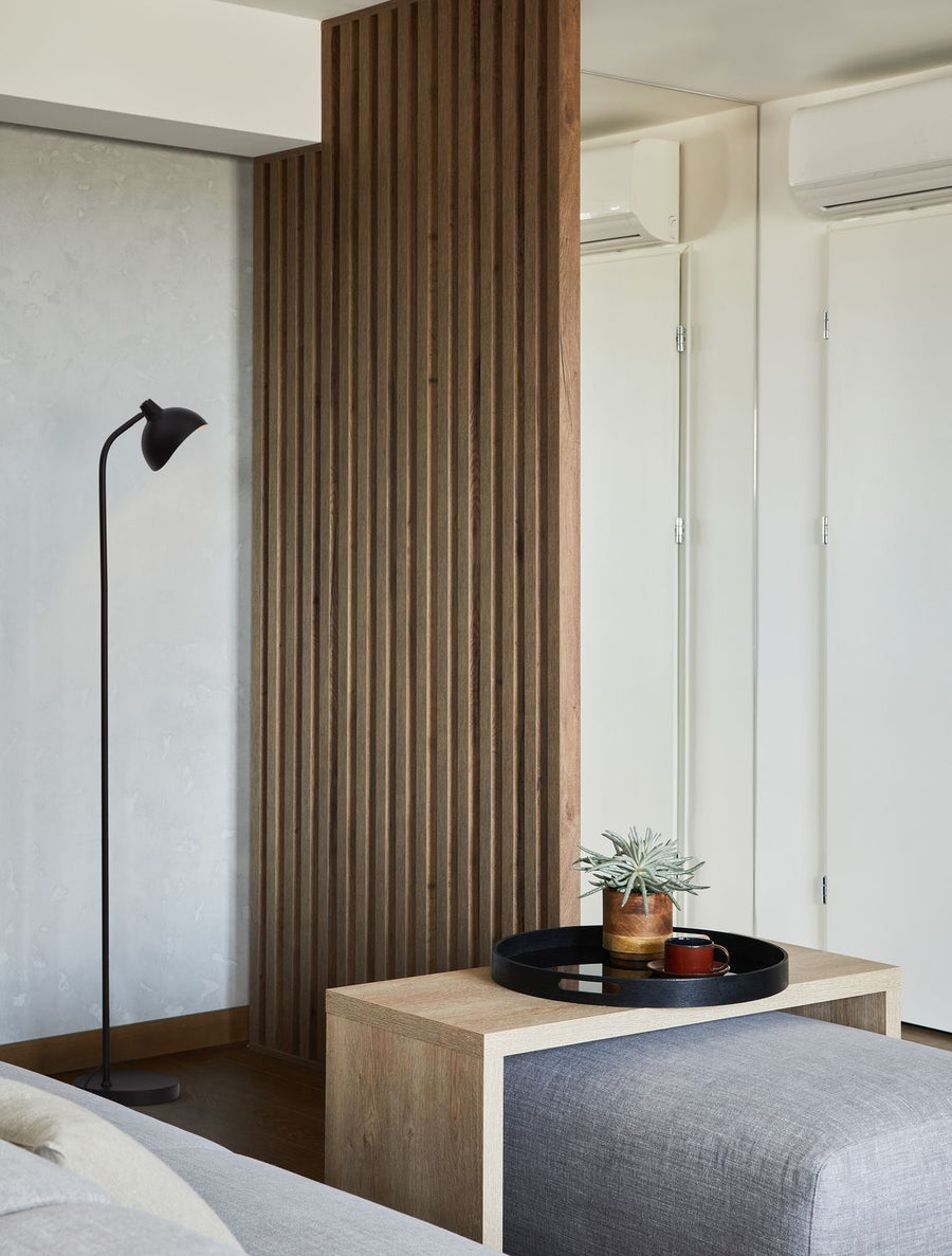 Lampadaire noir installé près d'un mur lambris bois dans un salon contemporain.