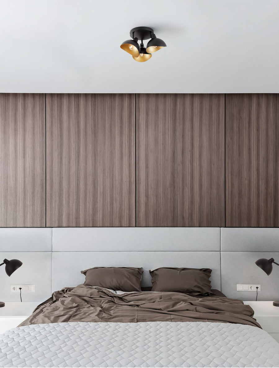 Plafonnier trois spots noirs installé au plafond d'une chambre au-dessus du lit