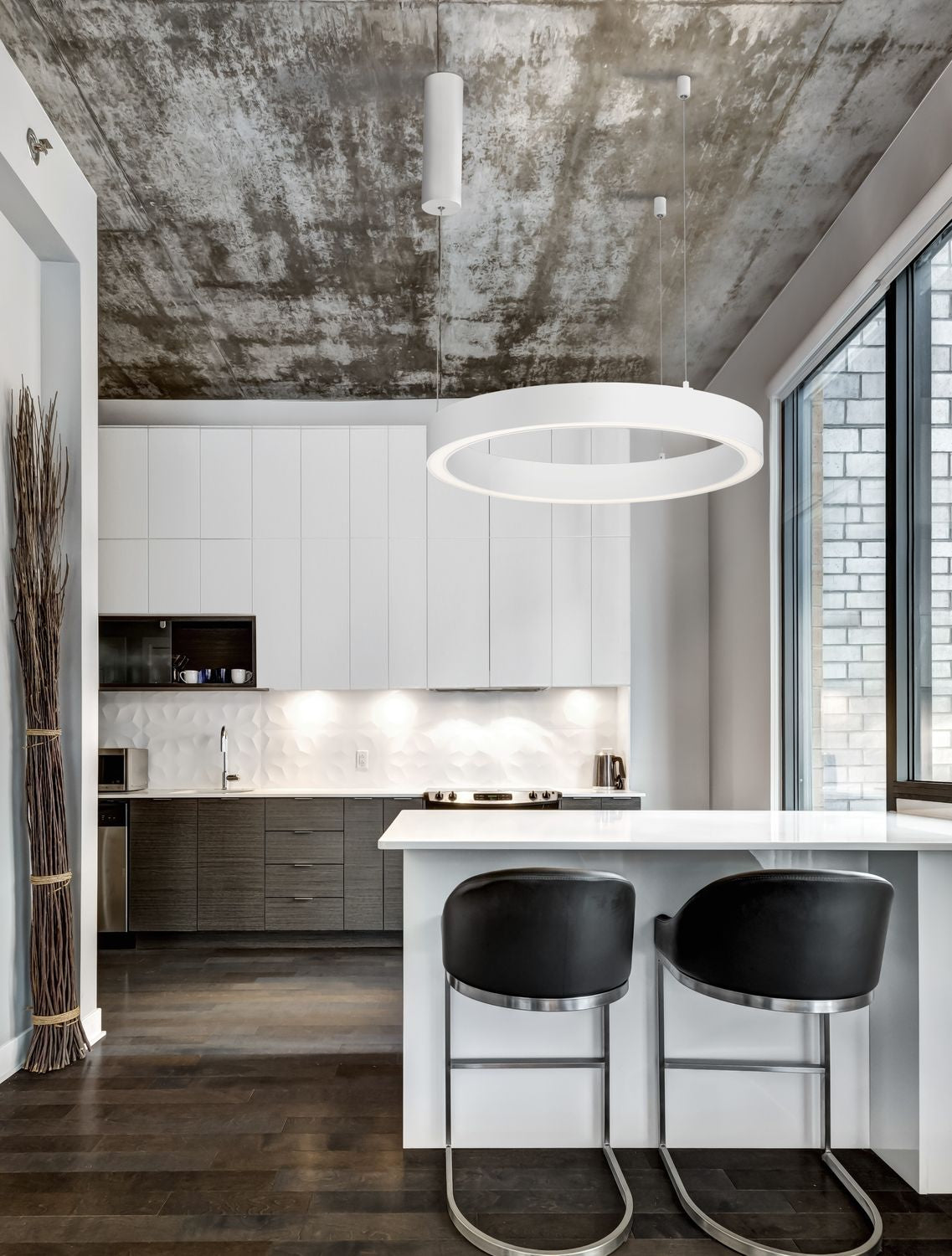 Suspension anneau blanche allumée au-dessus d'un îlot de cuisine, plafond béton
