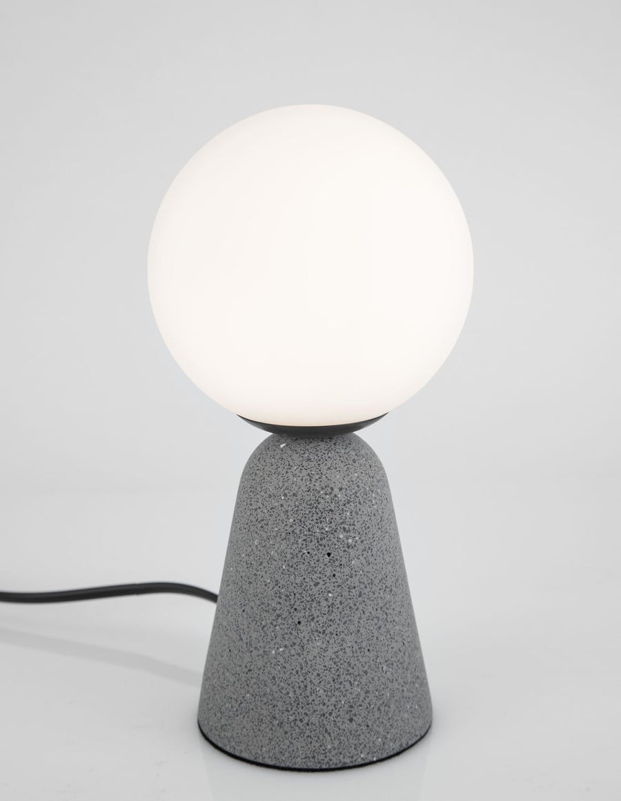 Vue de trois quarts de la lampe allumée, câble noir posé au sol