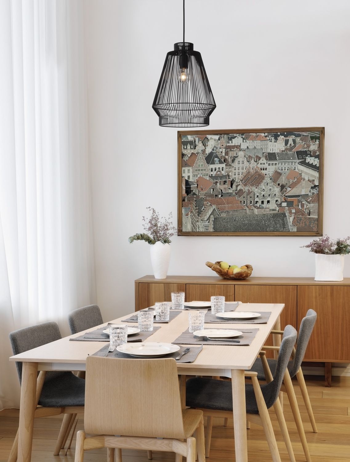 Suspension noire en cage suspendue au-dessus d'une table à manger en bois clair