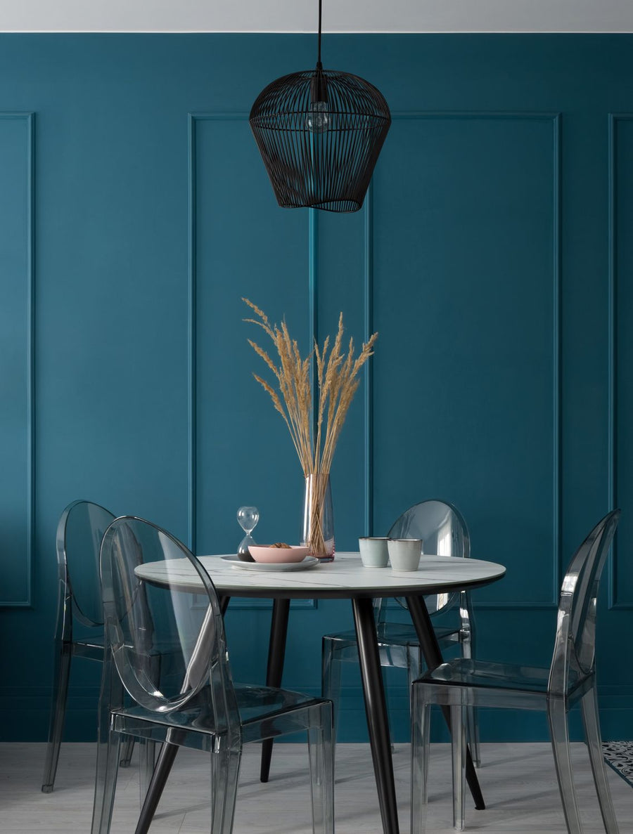 Suspension noire filaire suspendue au-dessus d'une table ronde dans une salle à manger bleu canard
