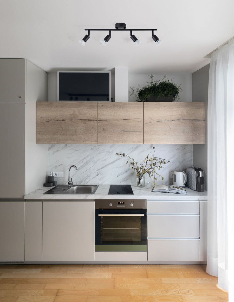 Plafonnier noir quatre spots orientables installé au plafond d'une cuisine moderne claire