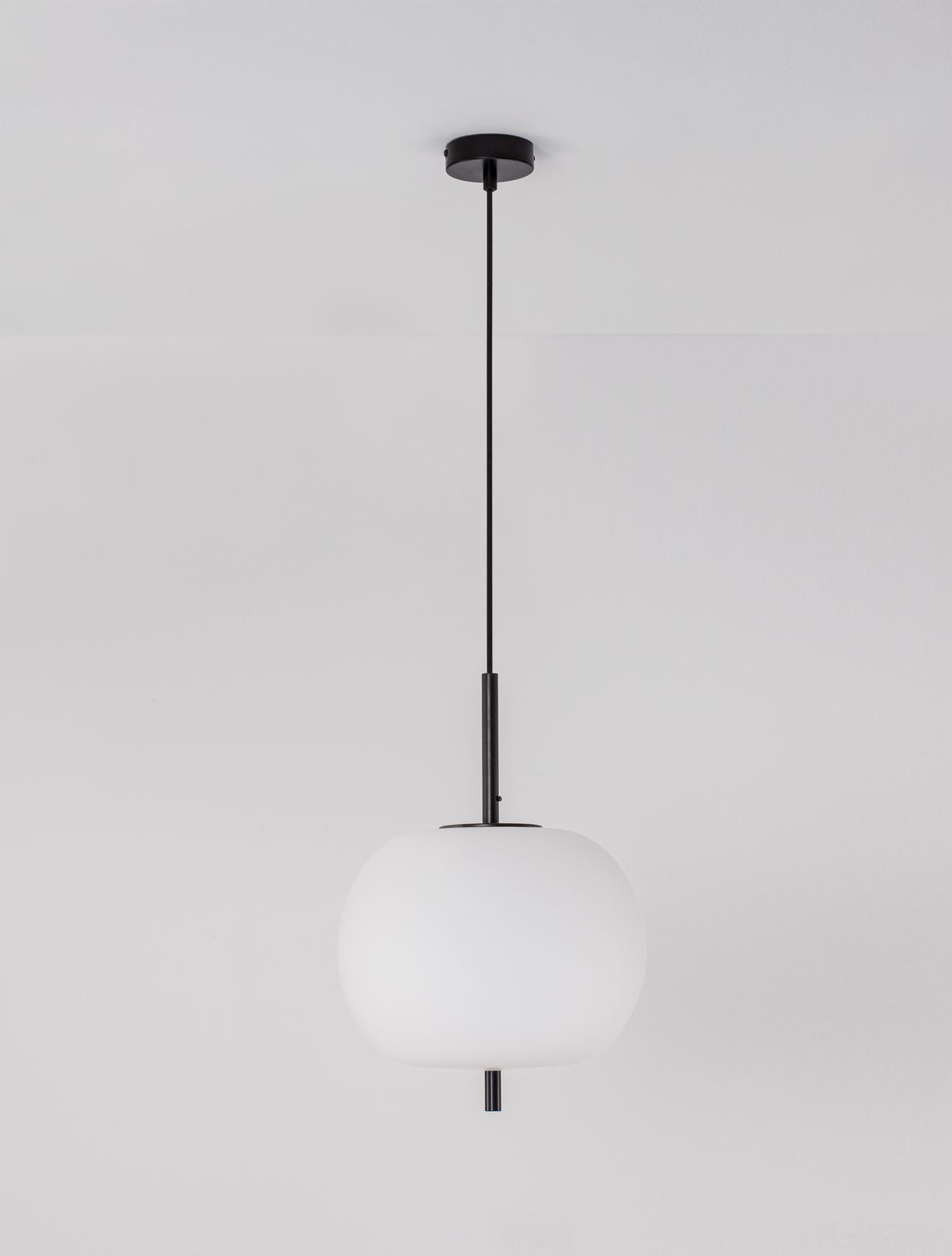 Suspension noire et globe de verre opalin photographiés de face sur fond gris