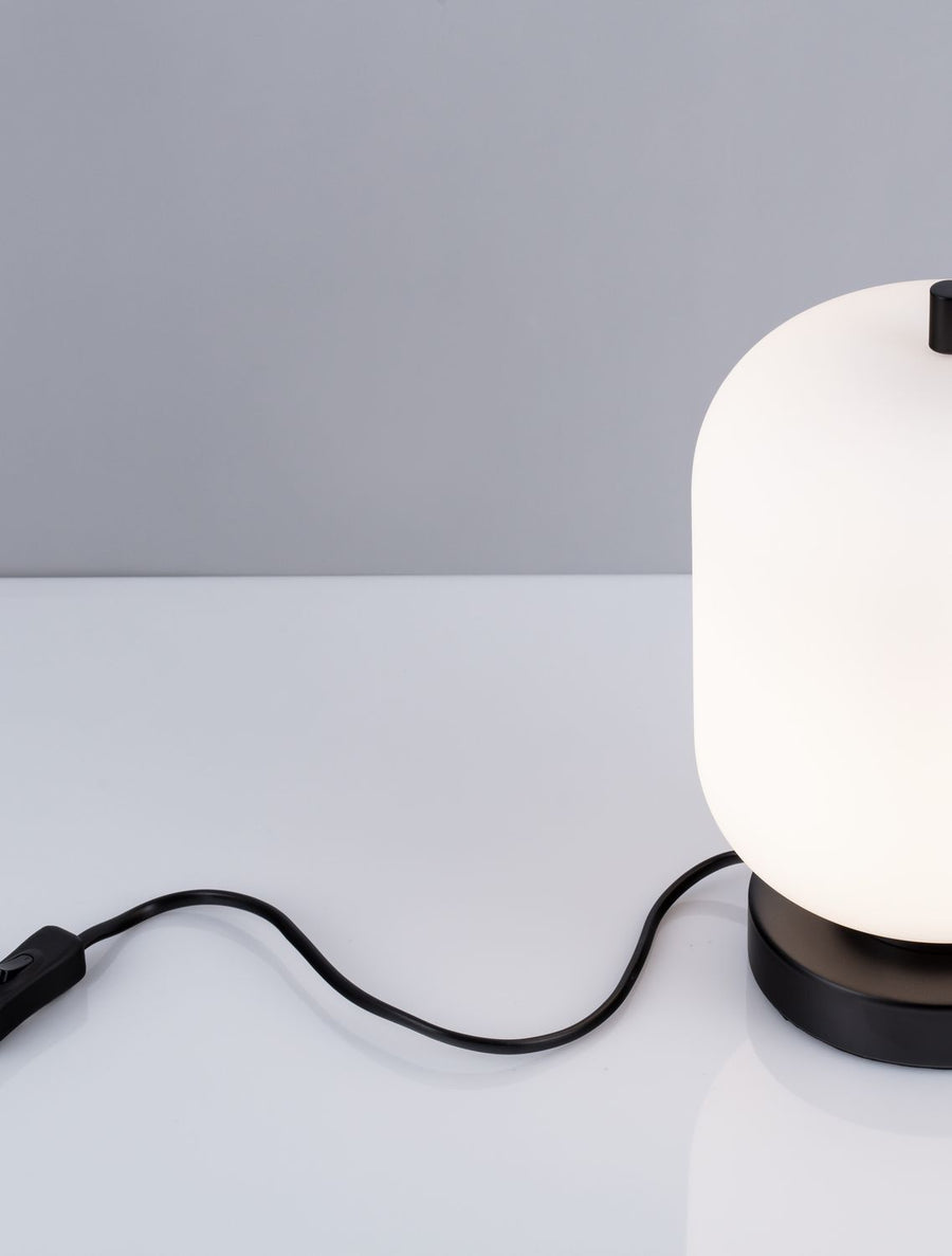 Détail du câble noir avec interrupteur, luminaire partiellement visible à droite.