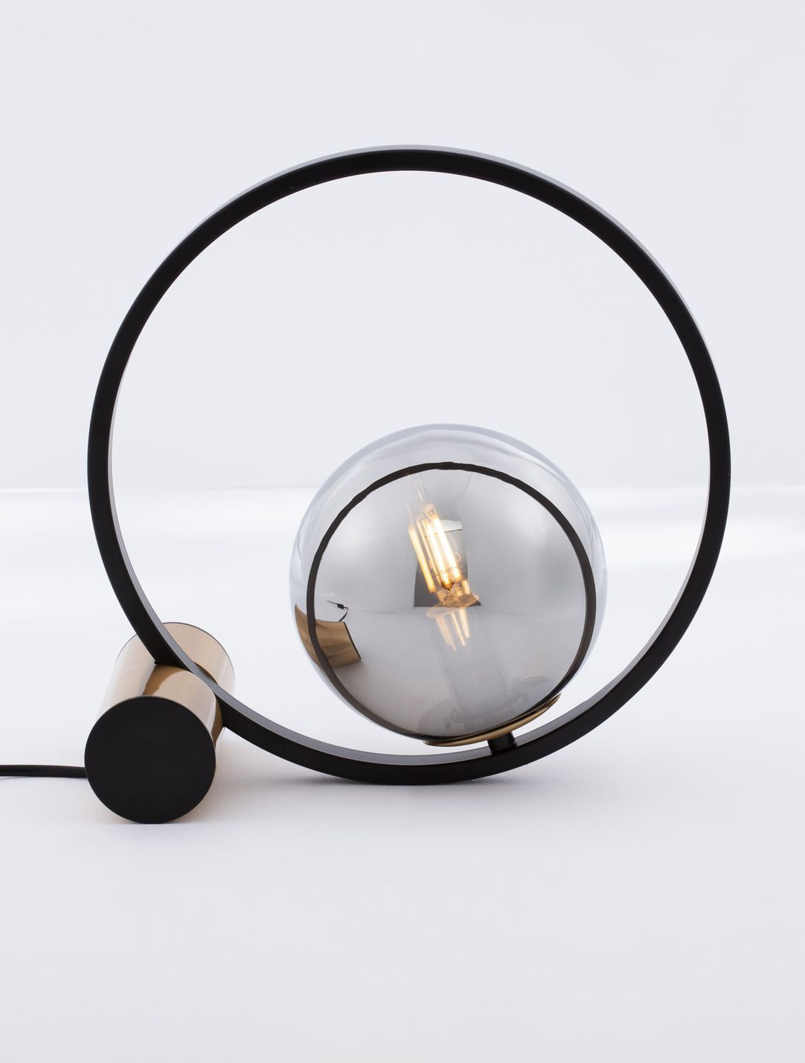 Lampe à poser de face, anneau noir et globe en verre fumé avec ampoule allumée