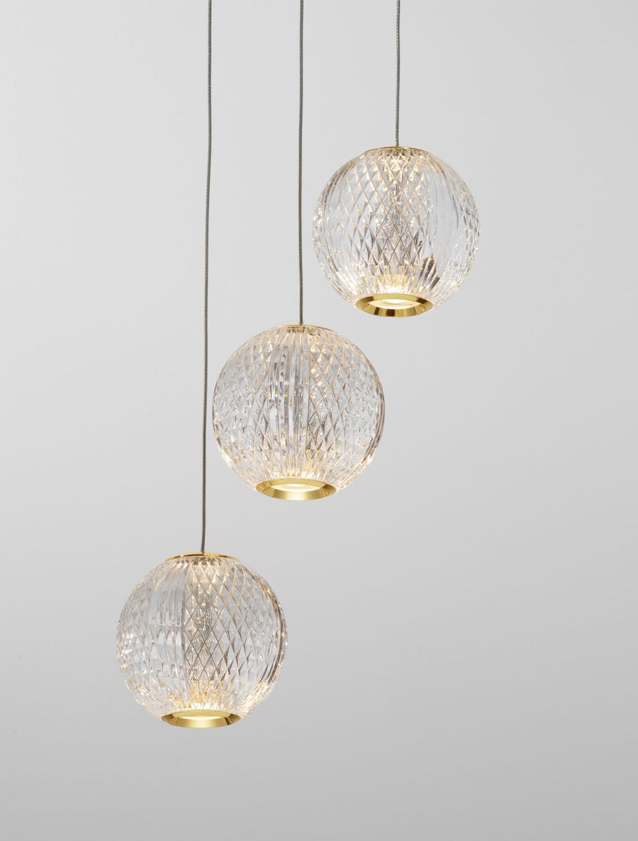 Gros plan sur les trois globes en verre facetté et leurs cerclages dorés