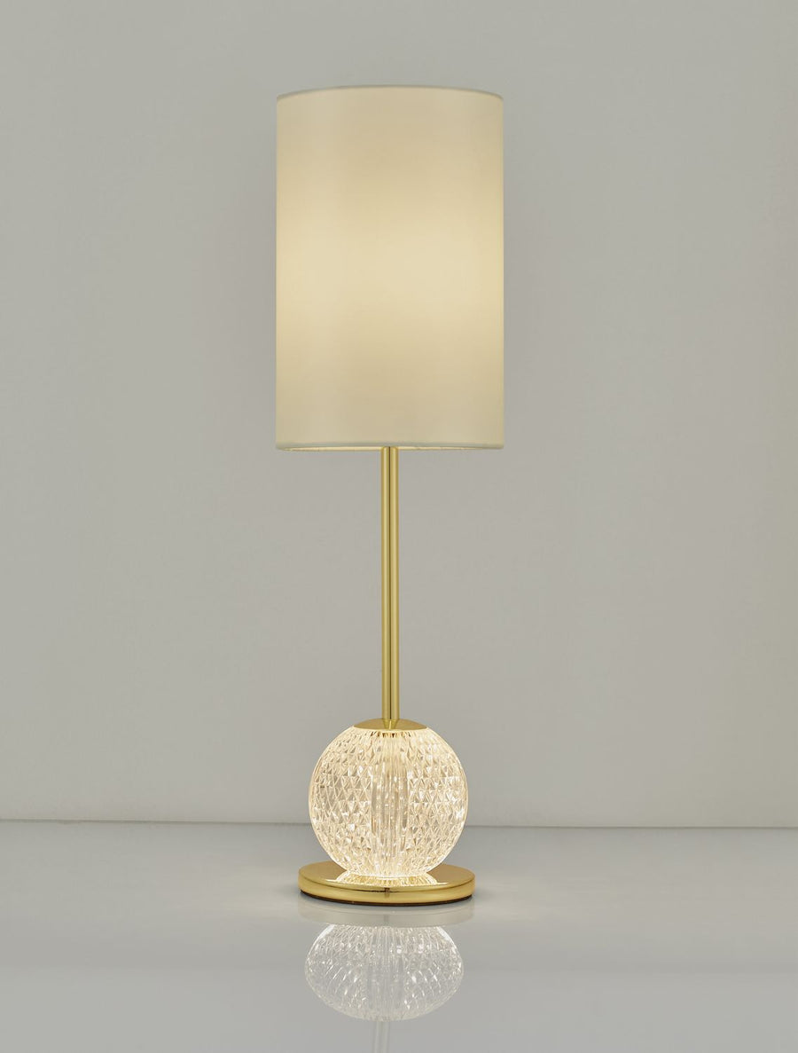 Lampe allumée, abat-jour diffusant une lumière chaude, reflet sur surface brillante