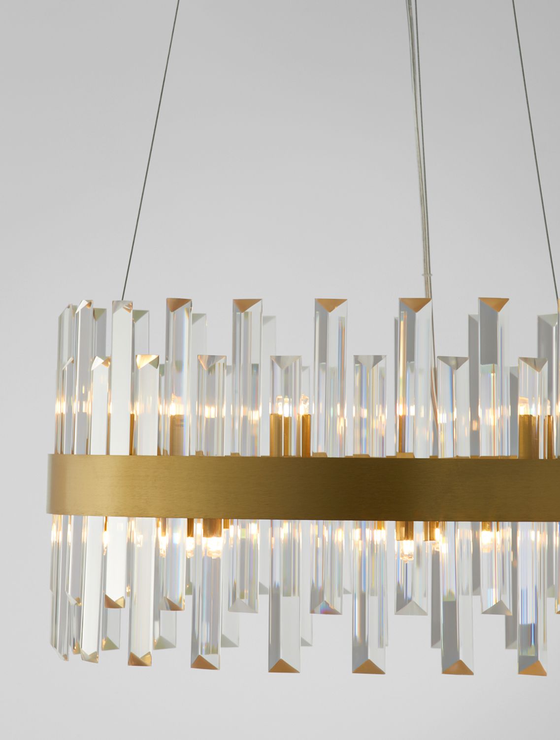 Détail rapproché du bandeau doré et des gouttes de cristal sur fond clair