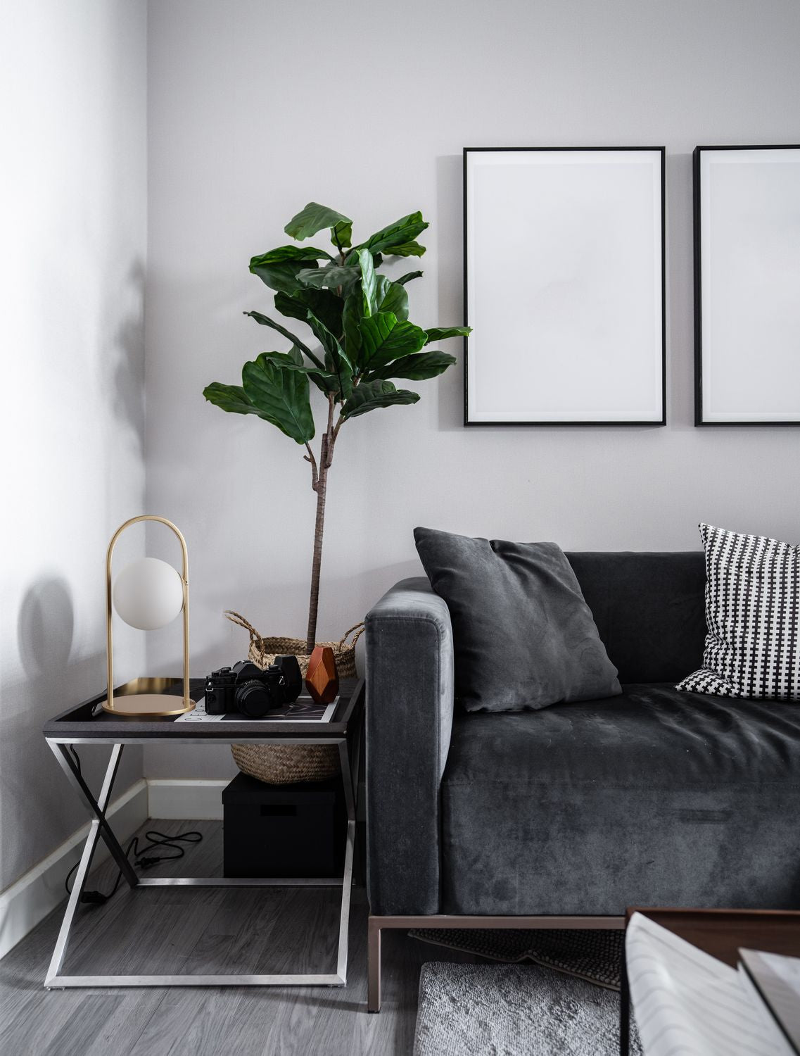 Lampe posée sur une table d'appoint noire dans un salon gris, près d'un fauteuil