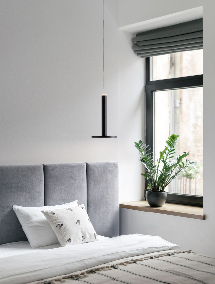 Suspension noire suspendue au-dessus d'une chambre à coucher avec lit gris et fenêtre