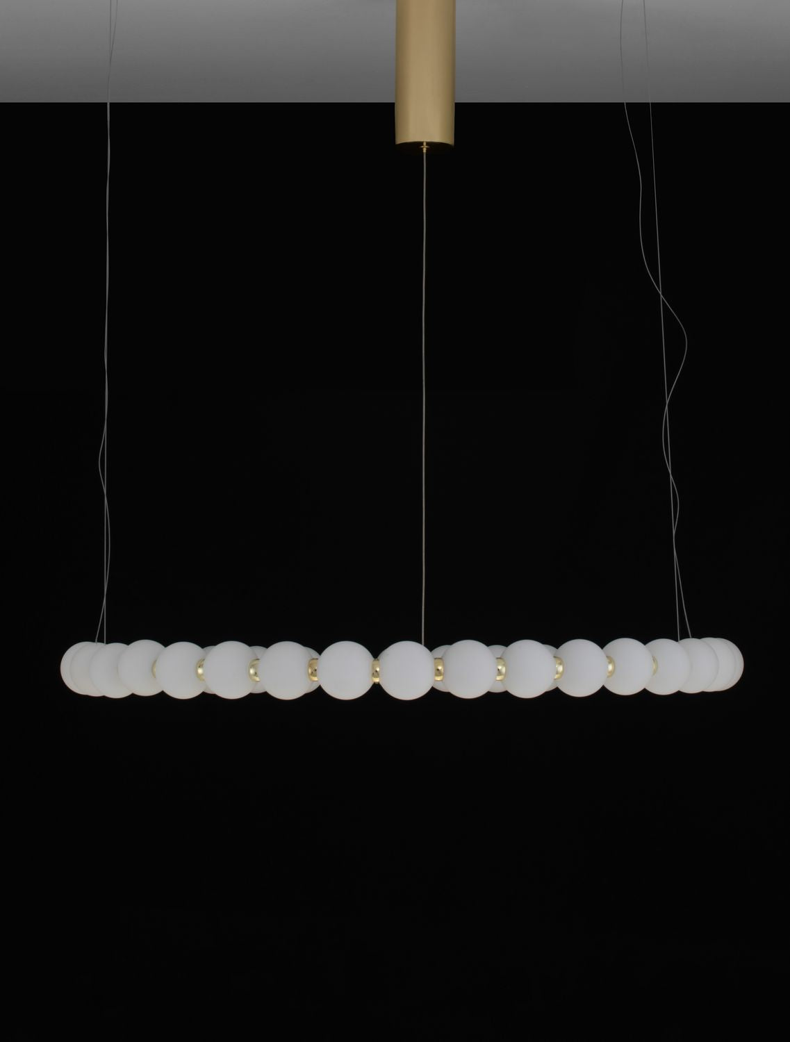 Produit de face sur fond noir, barre horizontale de sphères suspendue