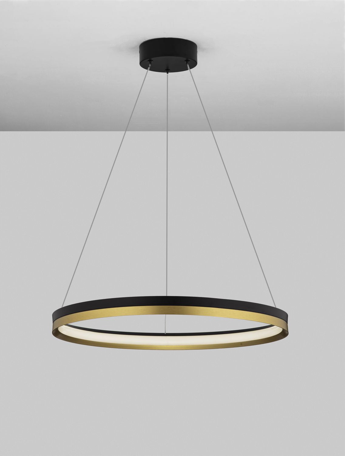 Suspension allumée sous plafond, halo lumineux blanc sous l'anneau noir et doré.