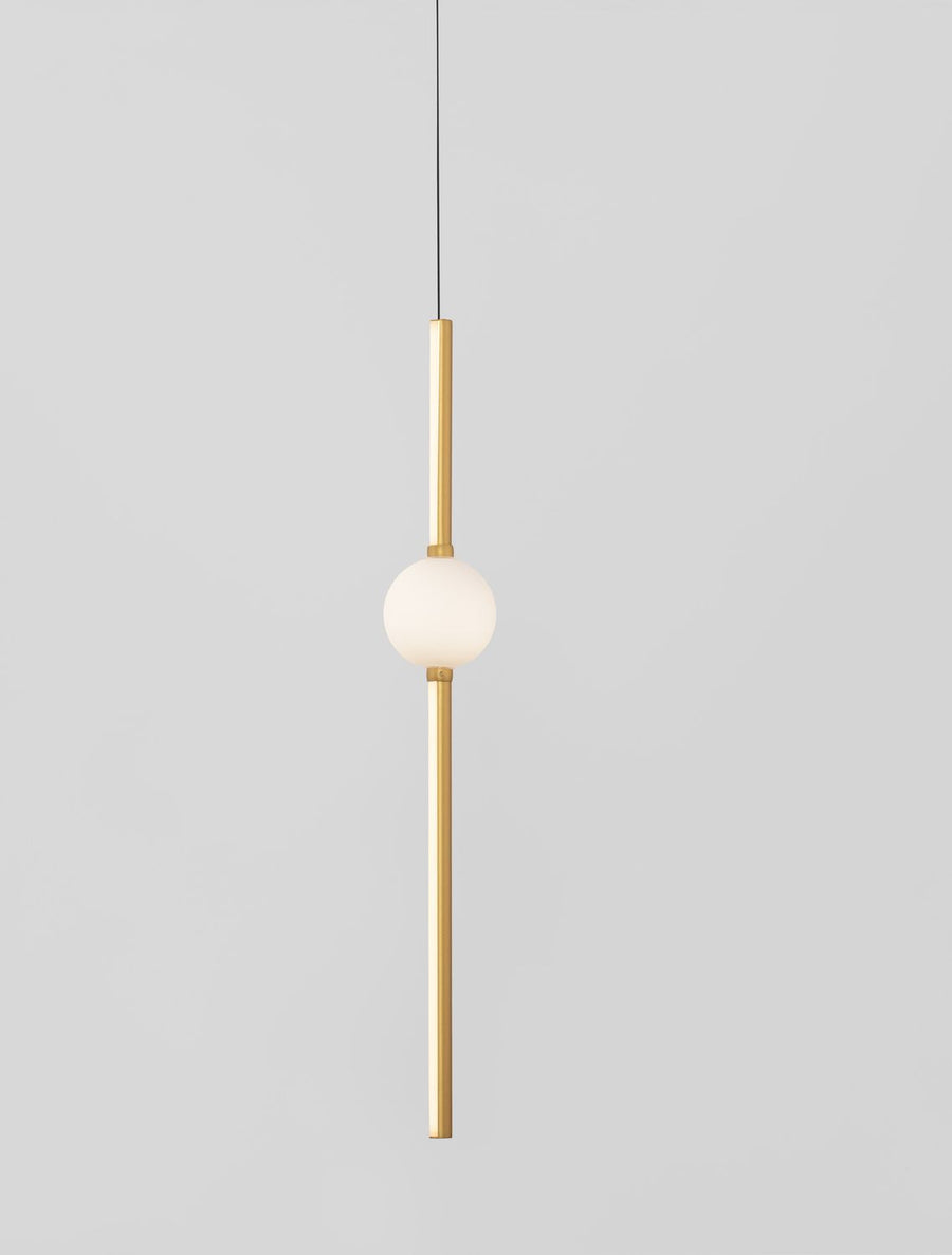 Gros plan sur la sphère blanche lumineuse et la tige dorée verticale du luminaire.