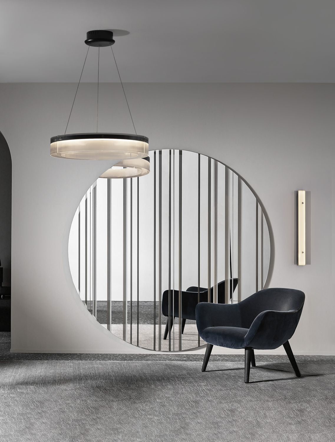 Suspension anneau allumée au-dessus d'un fauteuil bleu dans un intérieur contemporain