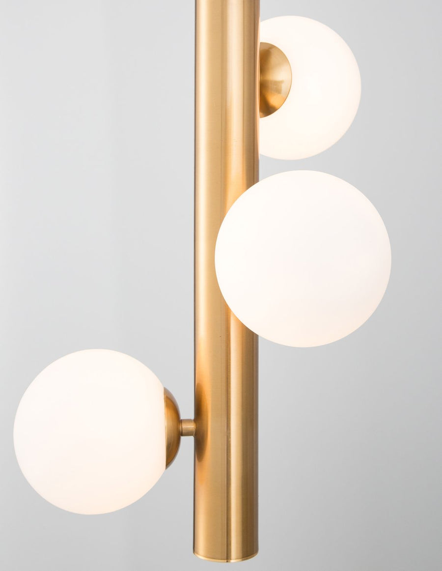 Trois globes lumineux allumés sur le corps cylindrique doré vertical, gros plan.