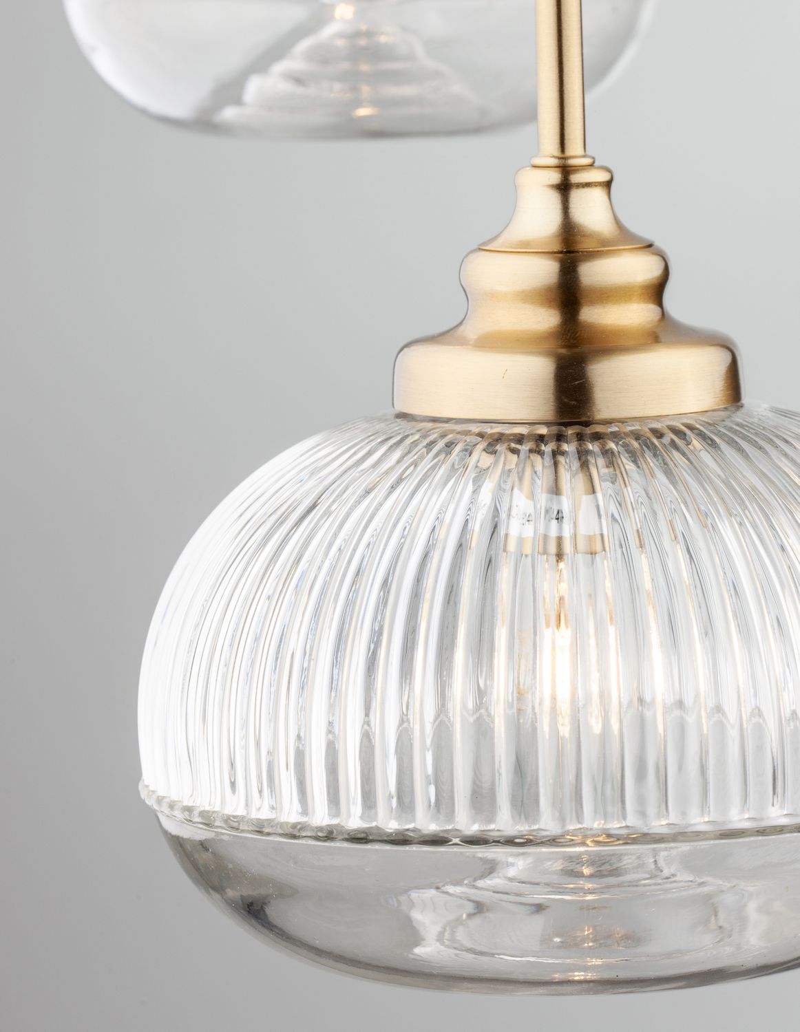 Gros plan sur l'abat-jour en verre strié et la douille dorée brillante