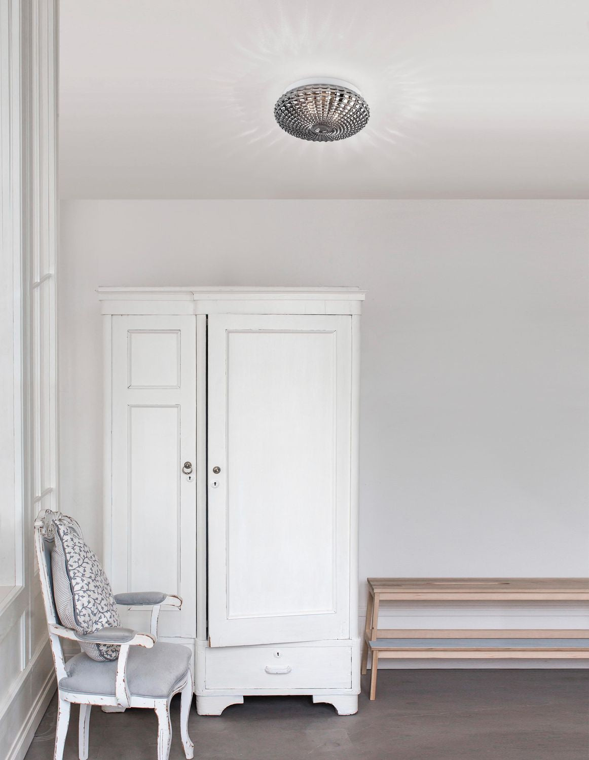 Plafonnier fumé installé au plafond d'une pièce blanche avec armoire et fauteuil