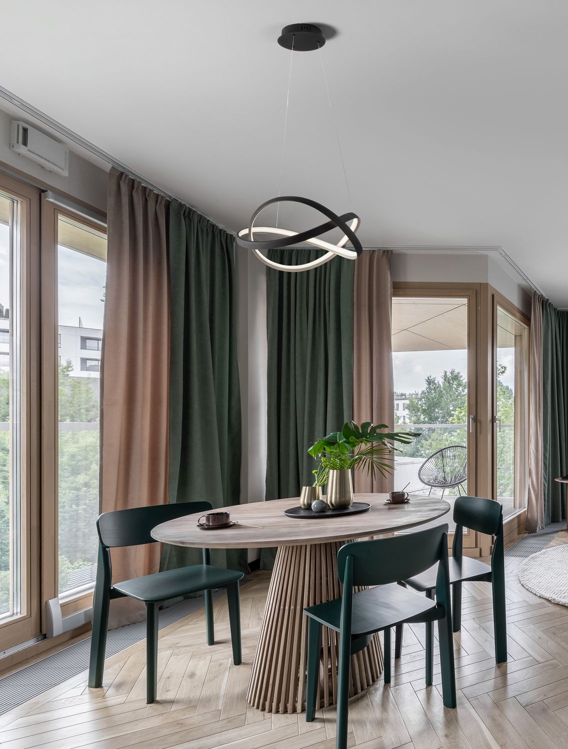 Suspension noire aux anneaux entrelacés éclairant une salle à manger contemporaine lumineuse