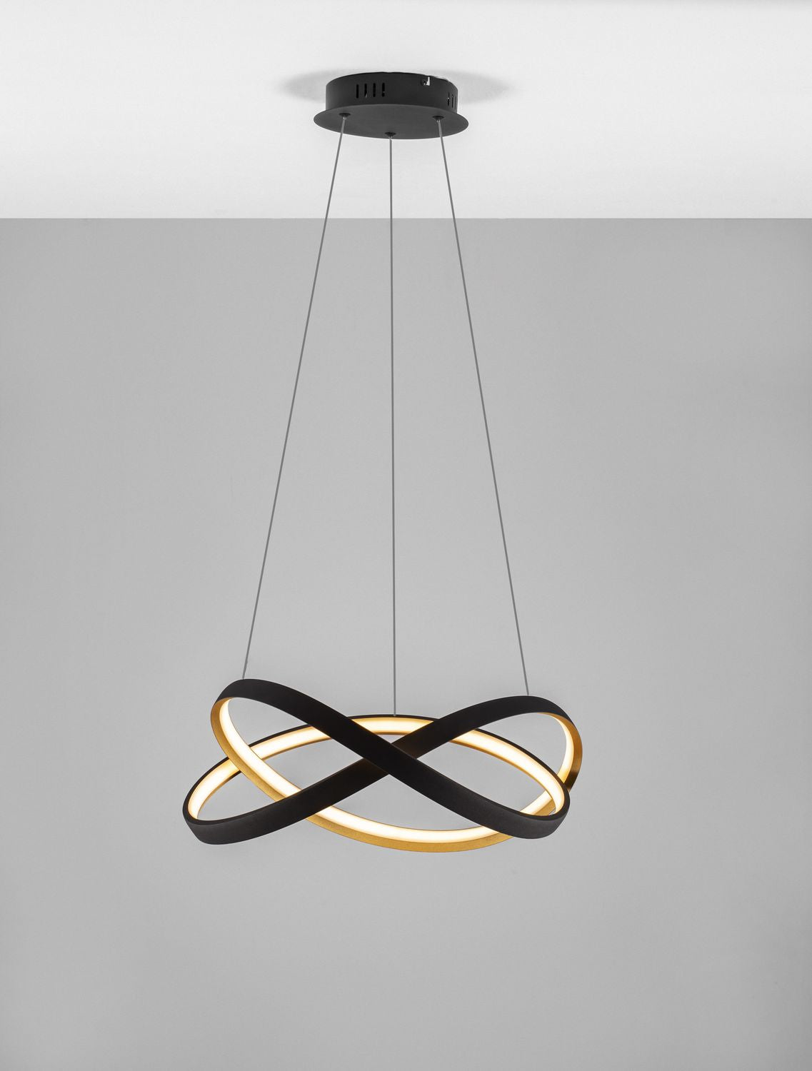 Suspension allumée sur fond gris, halo lumineux doré diffusé par les anneaux