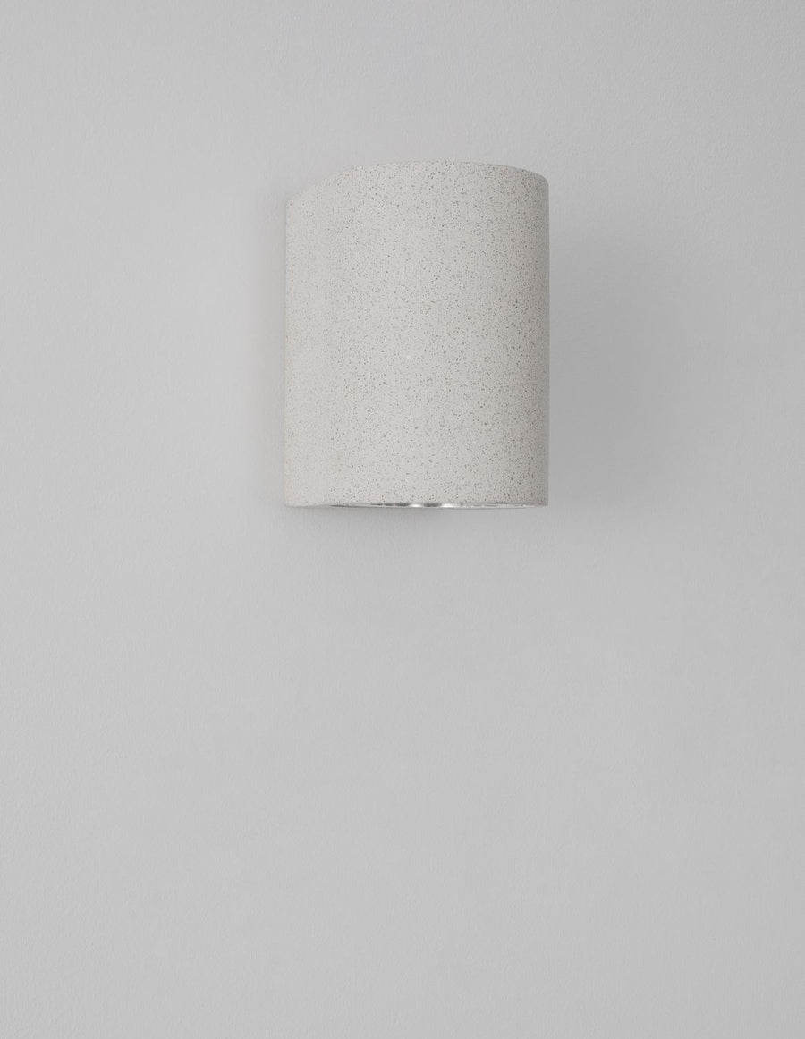 Vue de face non allumée sur mur gris, volume demi-cylindrique blanc cassé.