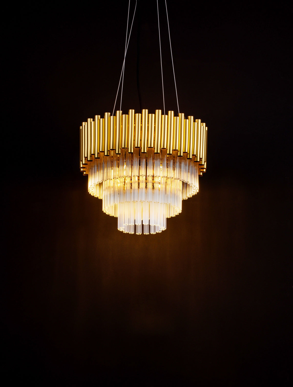 Luminaire suspendu allumé dans l'obscurité, révélant ses reflets dorés et cristallins