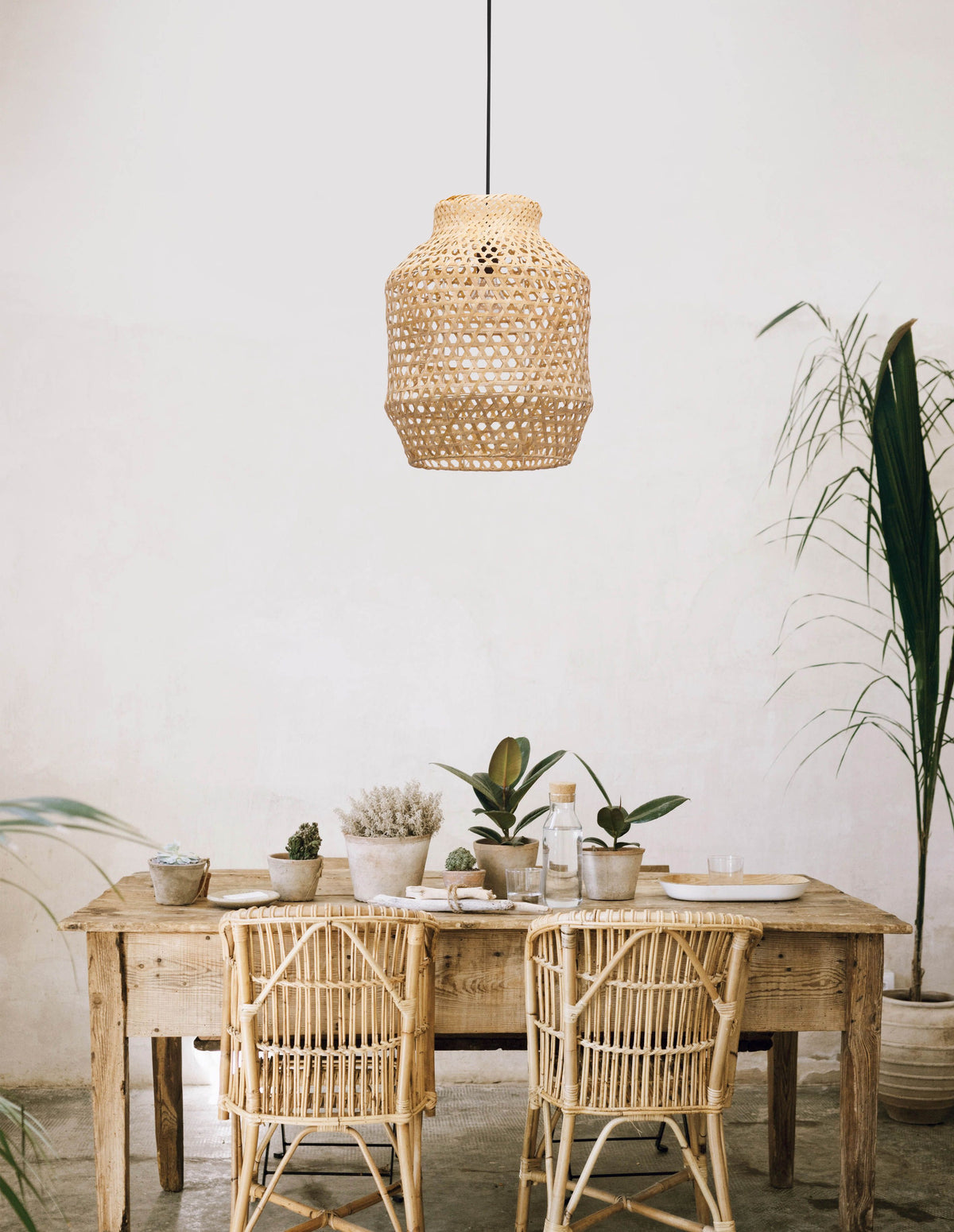 Suspension en rotin beige suspendue au-dessus d'une table en bois, ambiance bohème claire