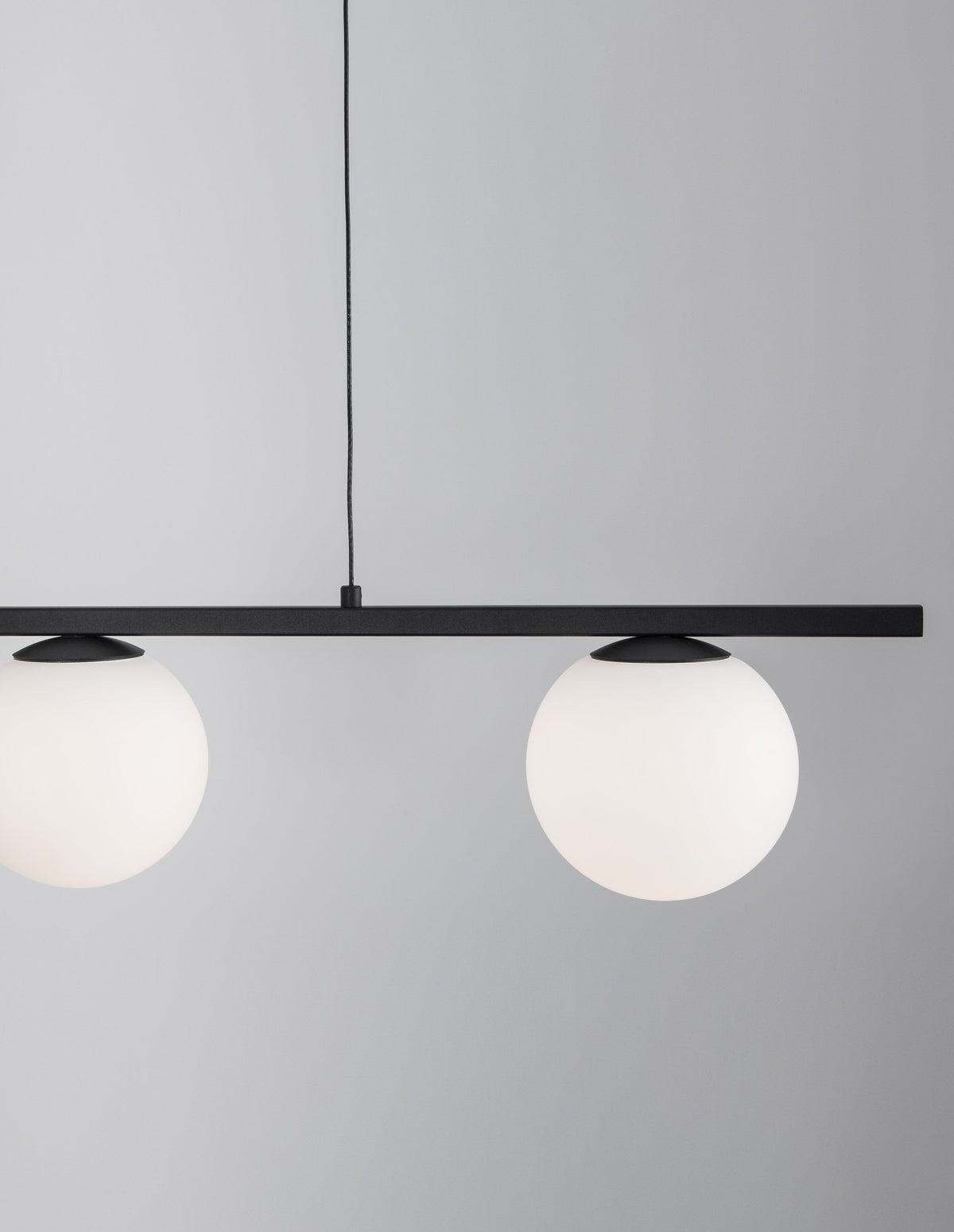 Détail rapproché de deux globes en verre dépoli et du câble de suspension