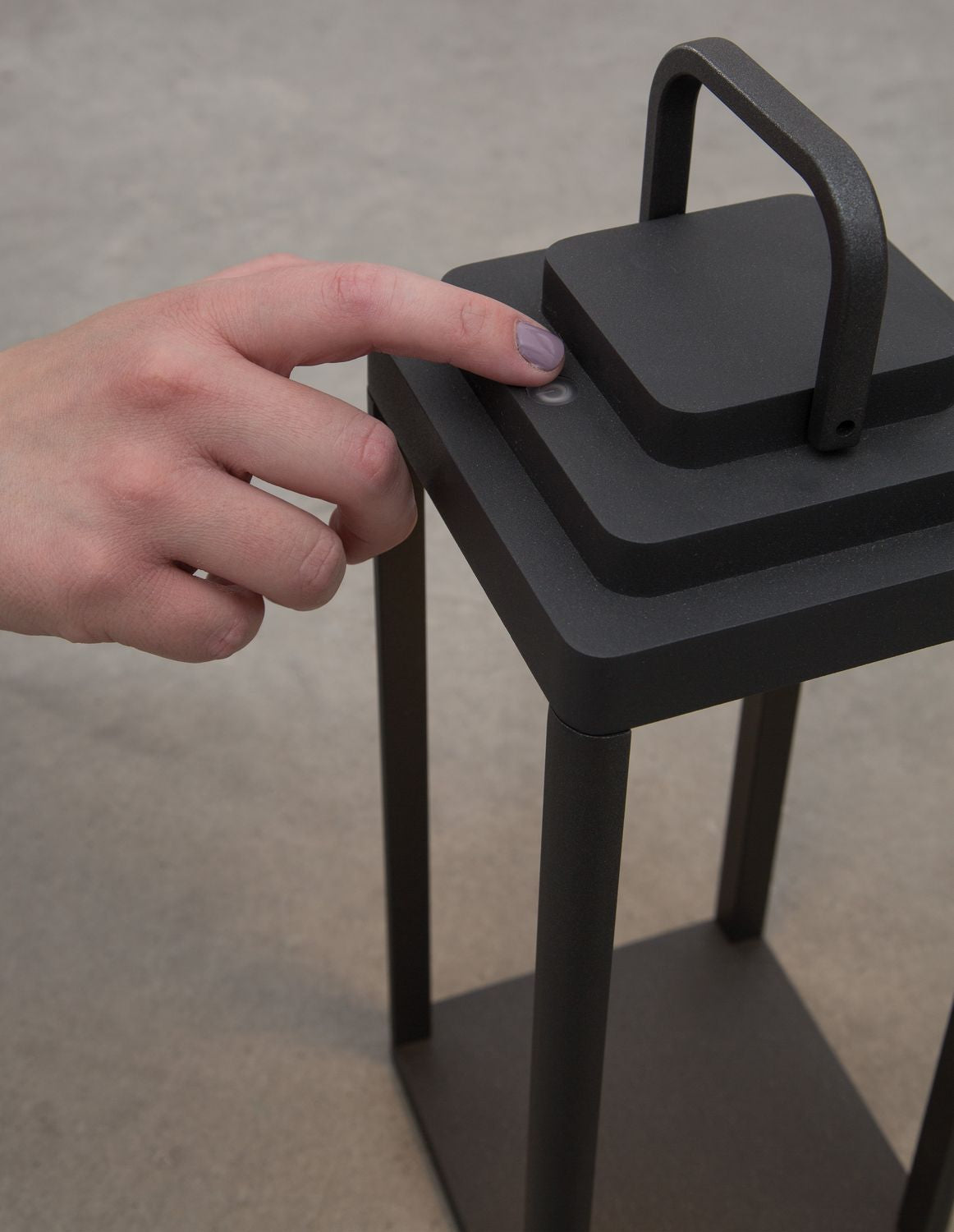 Main appuyant sur le bouton tactile situé au sommet du luminaire