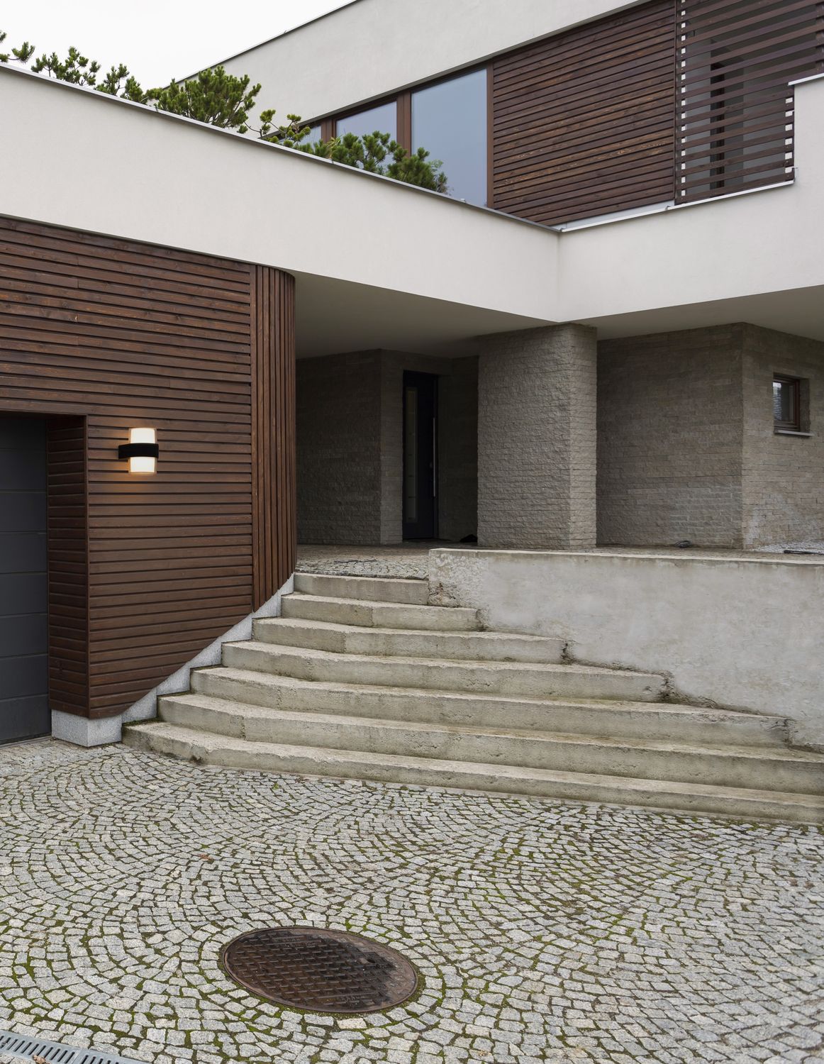 Applique noire allumée sur bardage bois d'une maison contemporaine, ambiance extérieure