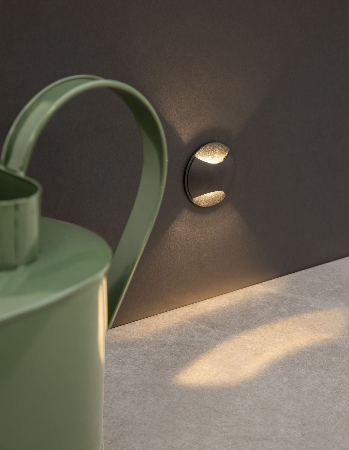 Applique murale noire ronde diffusant un halo lumineux haut et bas sur un mur sombre