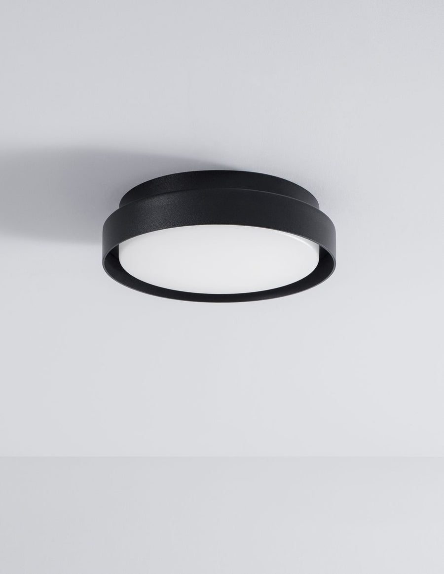 Le luminaire noir fixé au plafond blanc, éteint, photographié de dessous