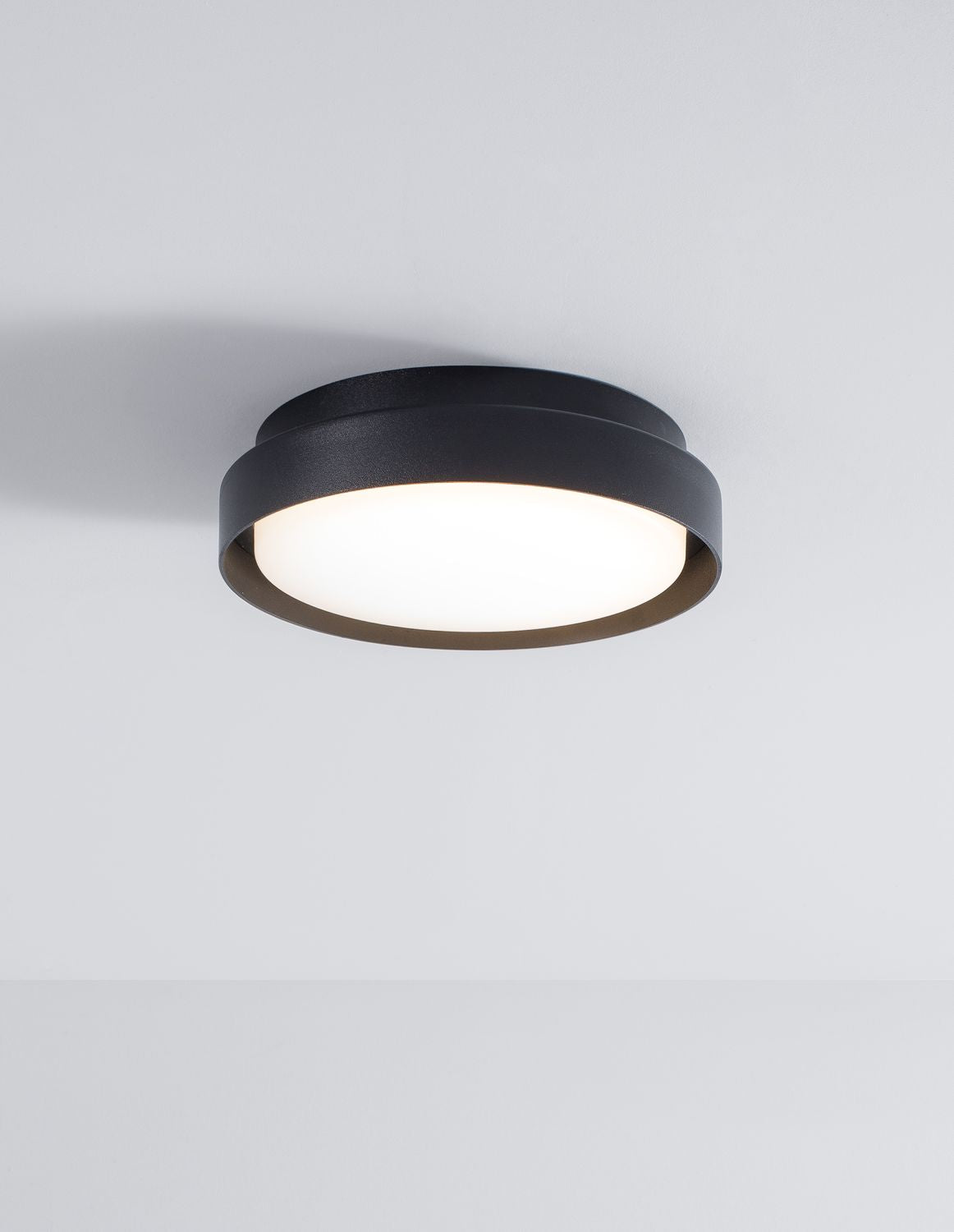 Même luminaire allumé, diffusant une lumière chaude sous un plafond blanc
