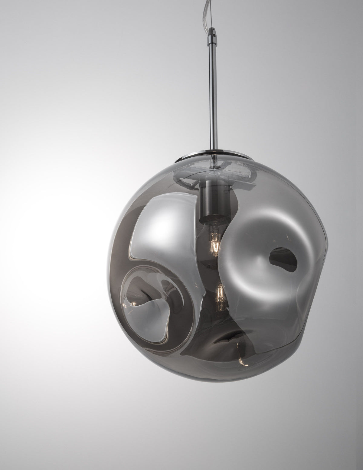 Suspension allumée avec sa sphère en verre fumé et ampoule apparente.