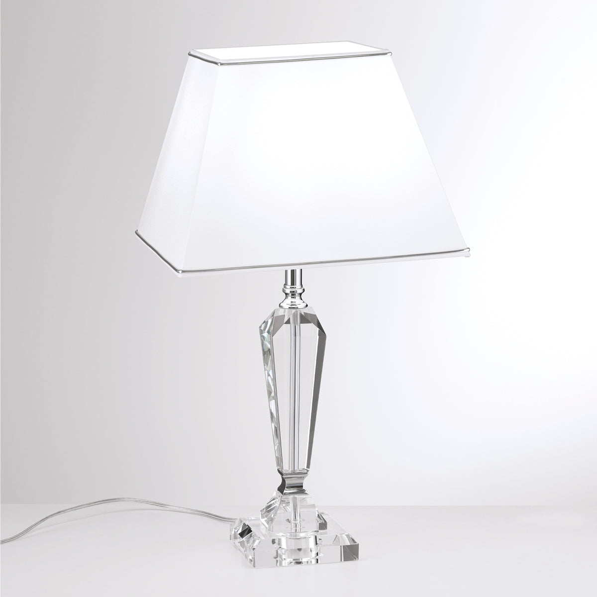 Lampe à poser blanche, abat-jour trapézoïdal et corps en cristal facetté, fond clair