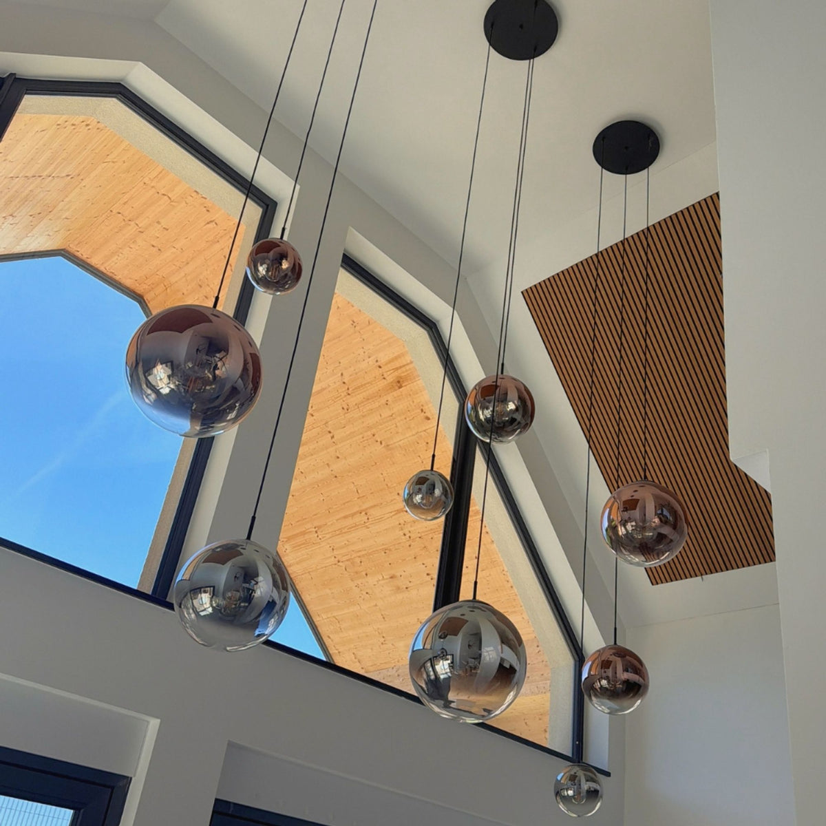 Grande hauteur sous plafond, plusieurs globes chromés suspendus à câbles noirs.