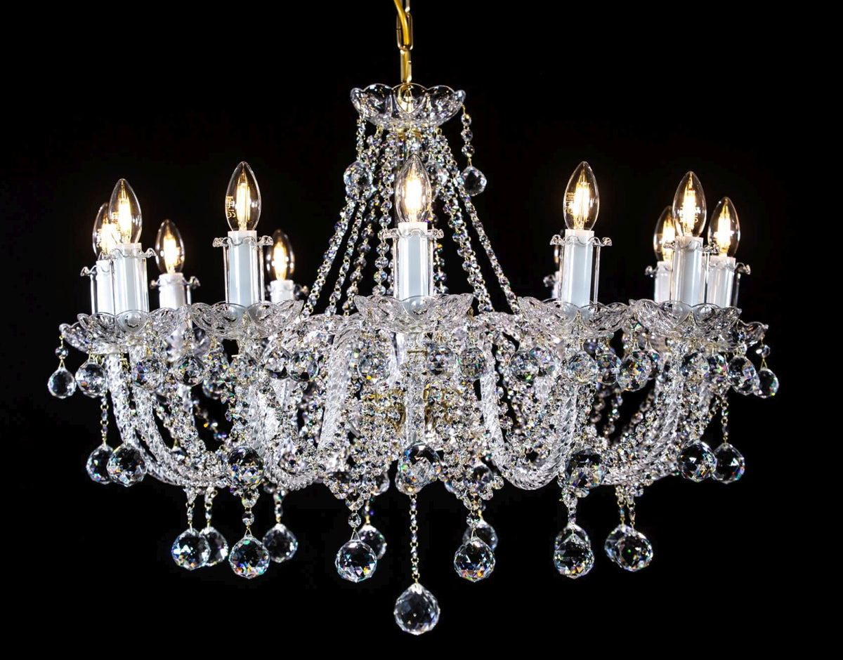 Lustre en cristal entier de face, tous les bras allumés sur fond noir