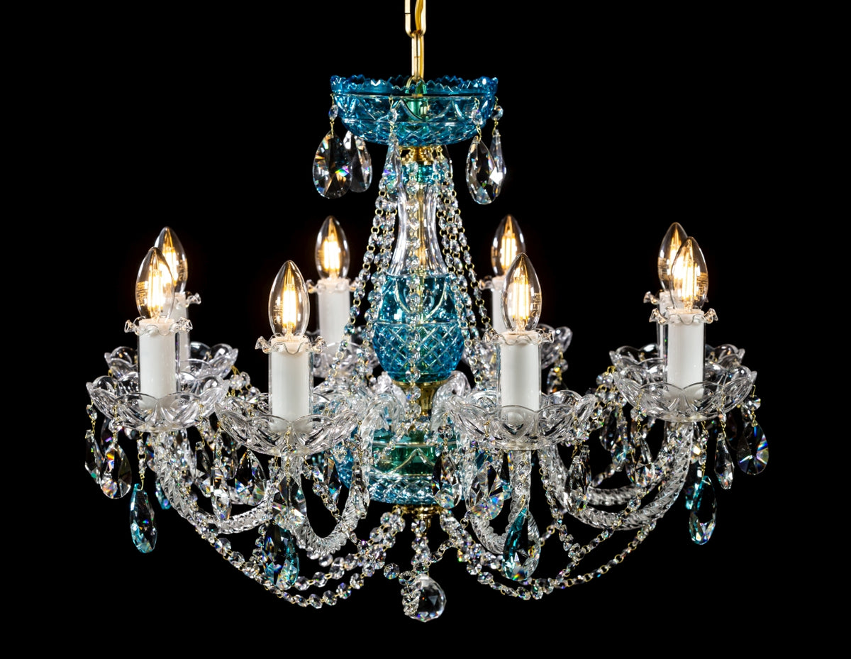 Lustre en cristal à six bras lumineux, pampilles bleues et transparentes, photographié sur fond noir.